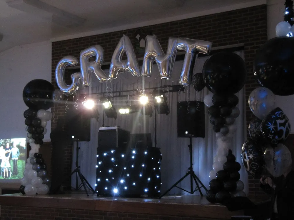 A Deluxe Discos mobile DJ rig with lighting and illuminated booth at a birthday celebration